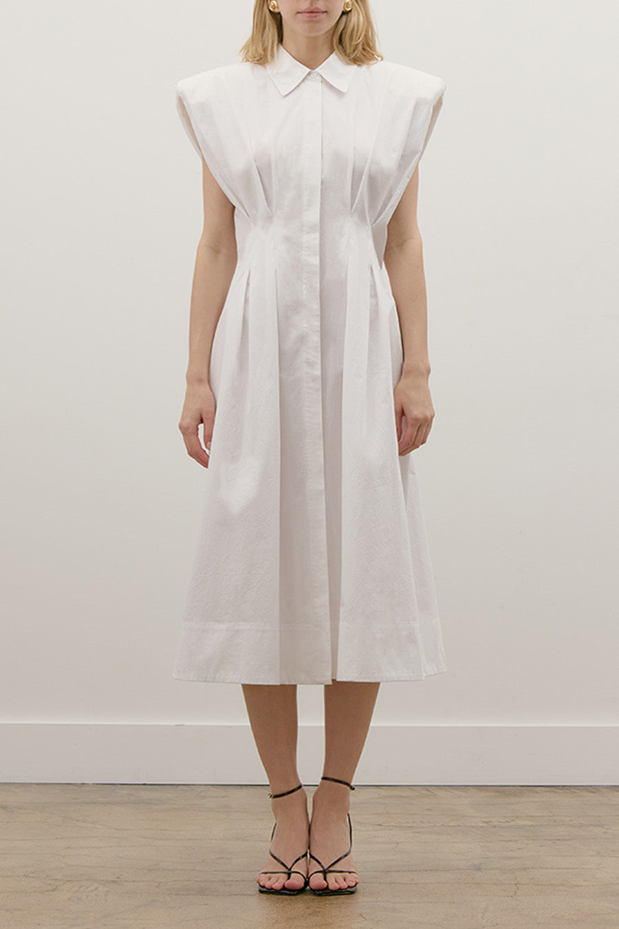 Thoughtfully placed vertical seams and sculpted pleats define the waist and flow into a softly flared midi skirt, enhancing movement and flattering the figure