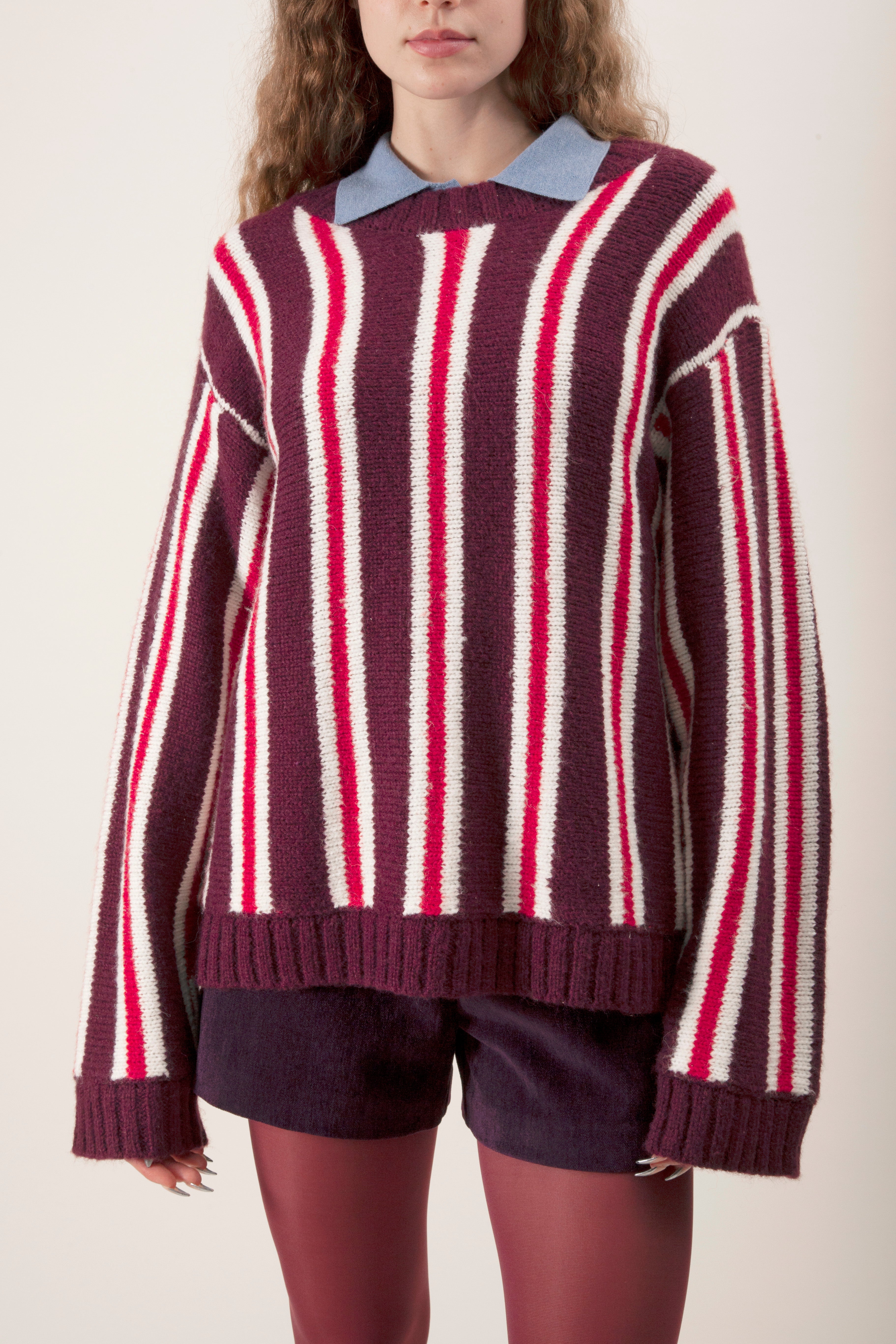 Featuring a rich burgundy base with contrasting vertical stripes in soft pink and ivory, this sweater delivers a bold yet timeless aesthetic.