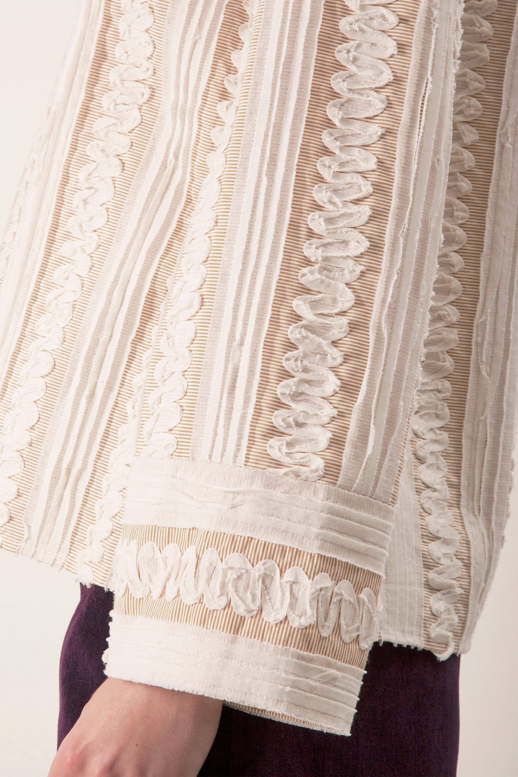 Subtle vertical detailing elongates the form, while gently flared sleeves add graceful movement and a touch of romance.