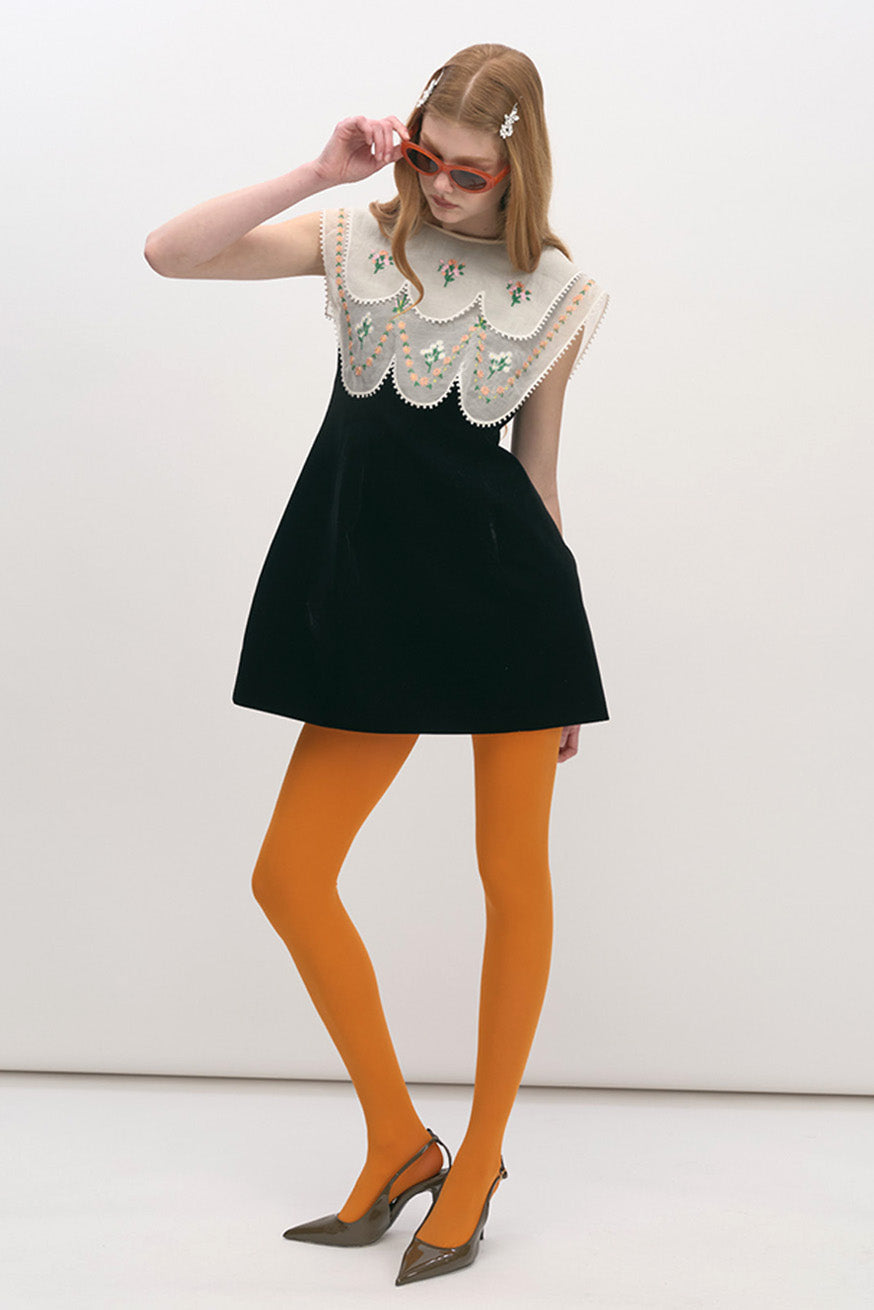 This statement mini dress is crafted with a refined sculptural silhouette, juxtaposing a sleek black body with an ornate embroidered bib.