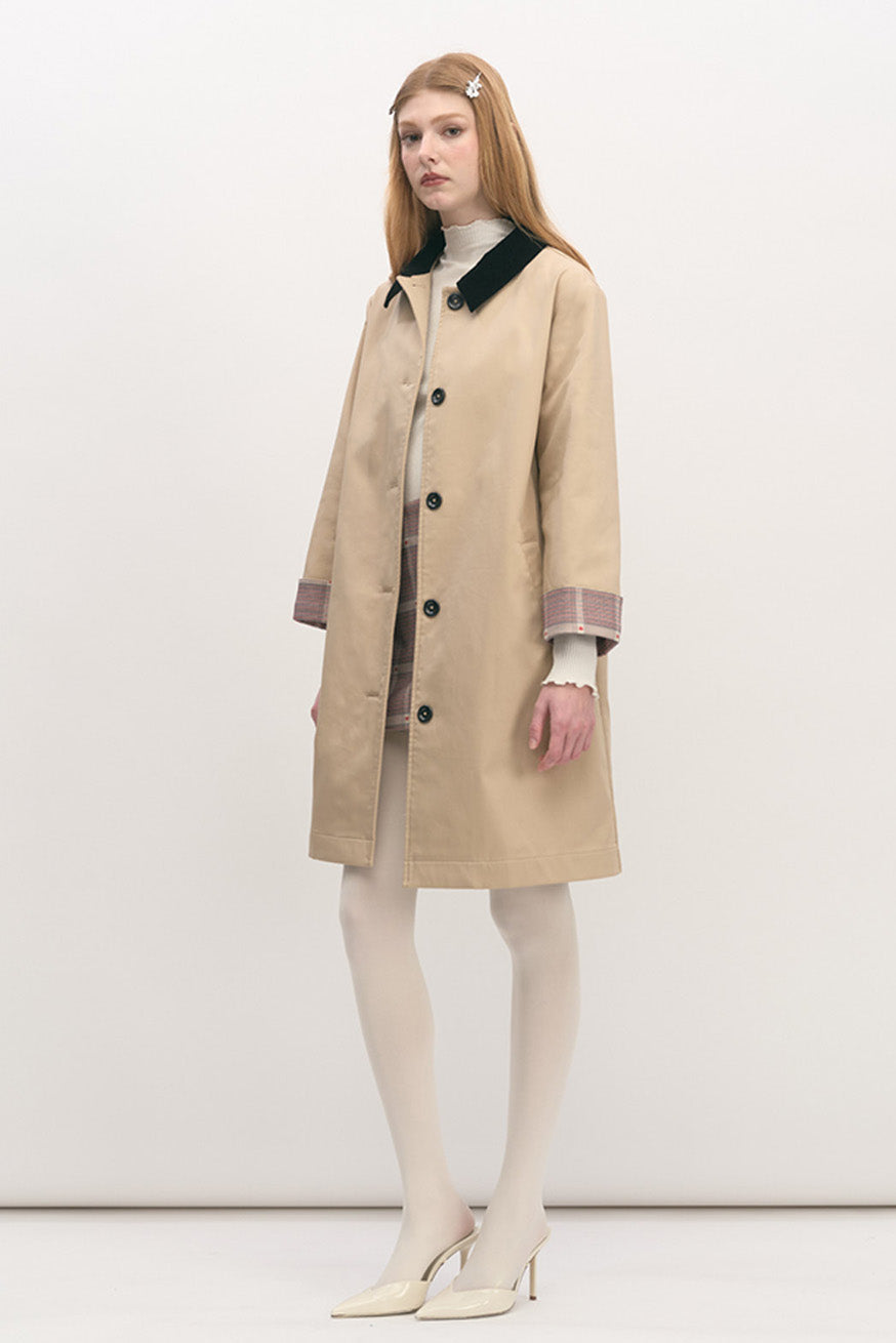 Designed with a clean, straight silhouette, it features a contrasting dark collar that adds graphic definition, while subtle plaid detailing at the cuffs offers a discreet nod to heritage tailoring.