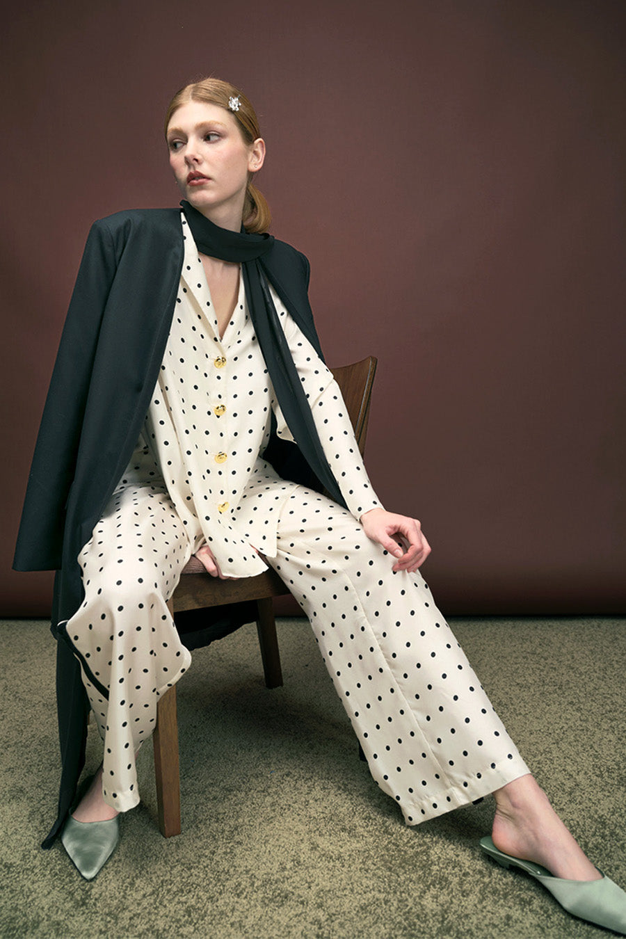 Designed with a relaxed silhouette, it features a softly structured collar and a row of polished gold-tone buttons that add a touch of understated opulence.