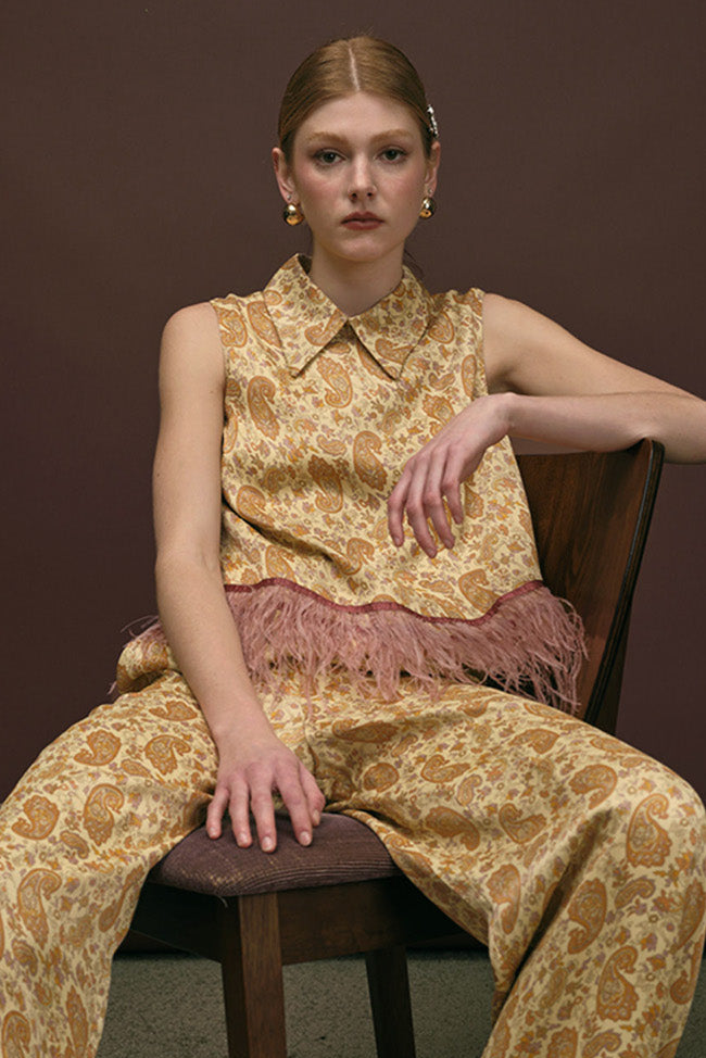 Designed with a sharp pointed collar and a structured silhouette, the piece is elevated by a delicate feather-trim hem that adds movement and modern contrast.