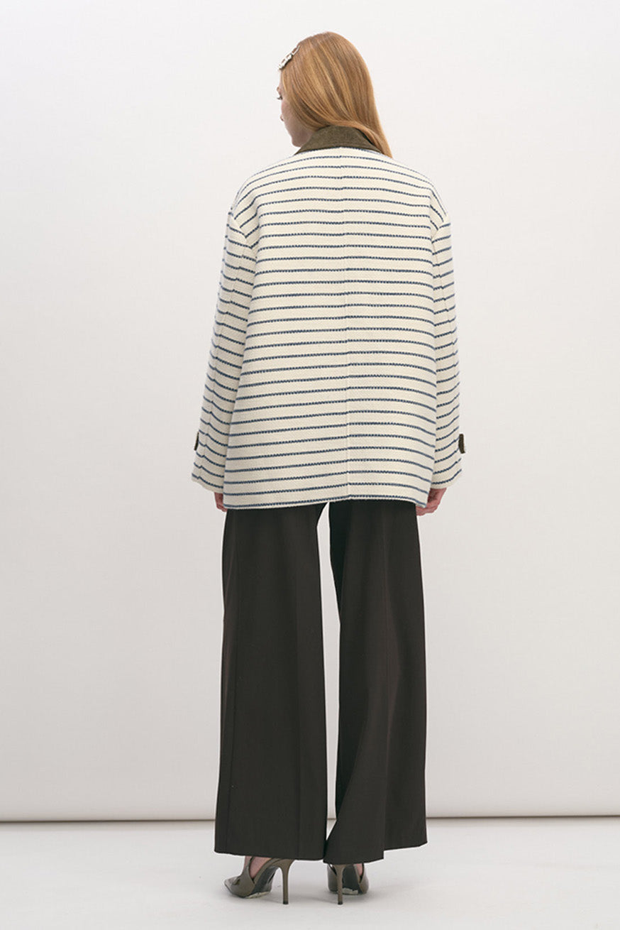 Oversized flap pockets and a clean button-front silhouette add a utilitarian edge, while the contrast collar introduces a subtle nod to heritage craftsmanship.