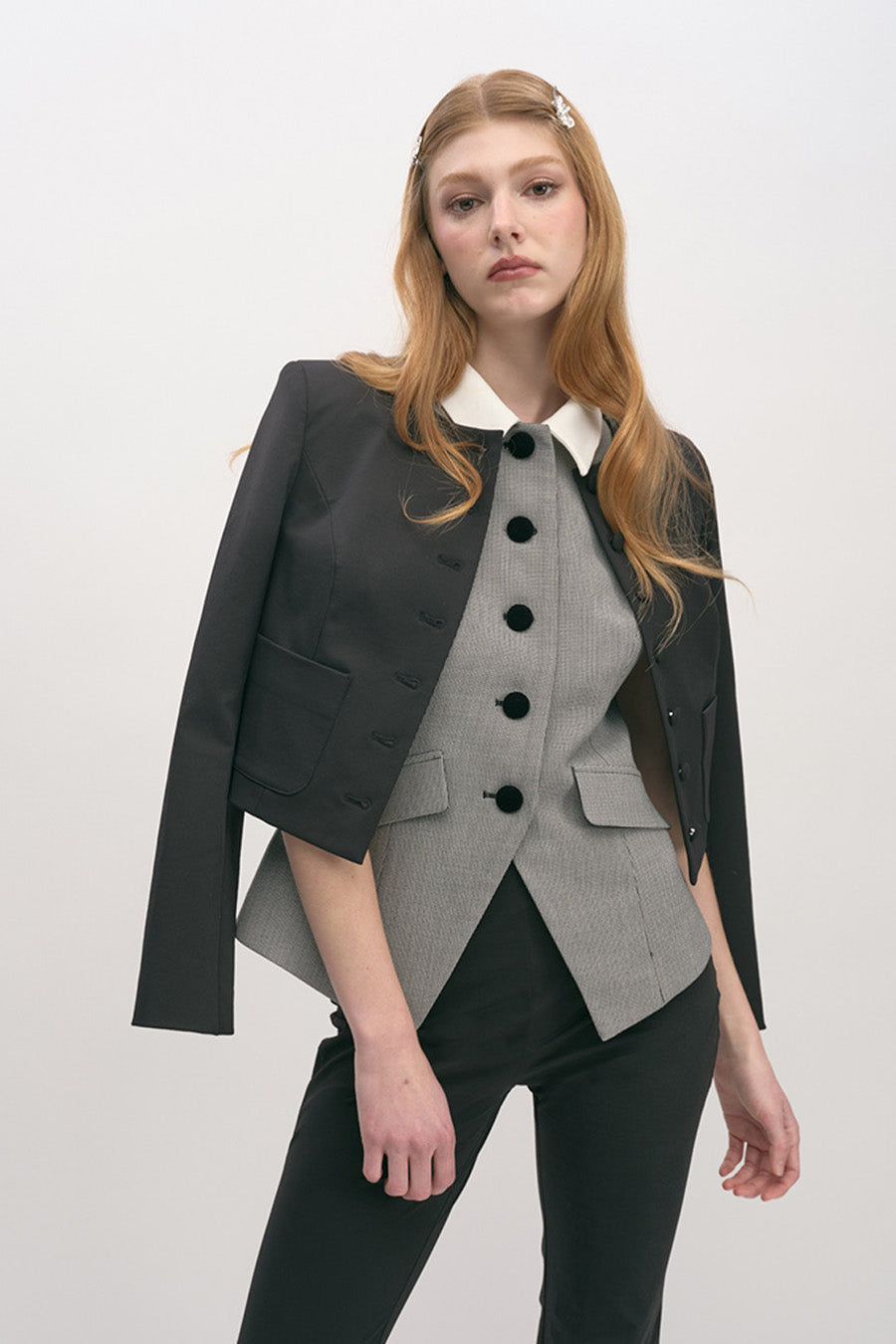 The structured silhouette is balanced by subtle flared panels at the hem, creating an elegant shape that flatters while maintaining a strong, tailored presence.