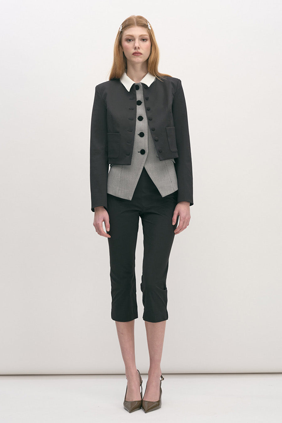 This refined cropped jacket is impeccably tailored in a deep black fabrication, defined by its structured silhouette and precise craftsmanship.