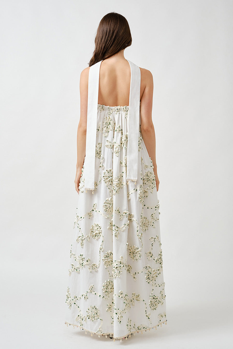 Intricately applied floral embellishments cascade across the sheer, airy layers, adding dimension, texture, and couture-inspired detail