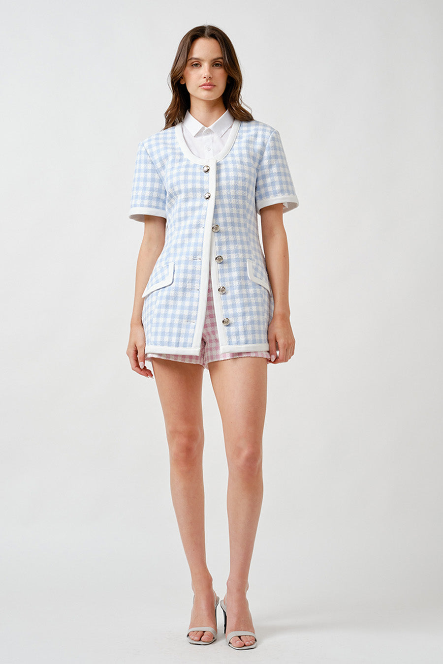 Designed with a softly contoured silhouette, it features contrast ivory trim, a clean neckline, and elegant statement buttons that lend a jewelry-like finish.