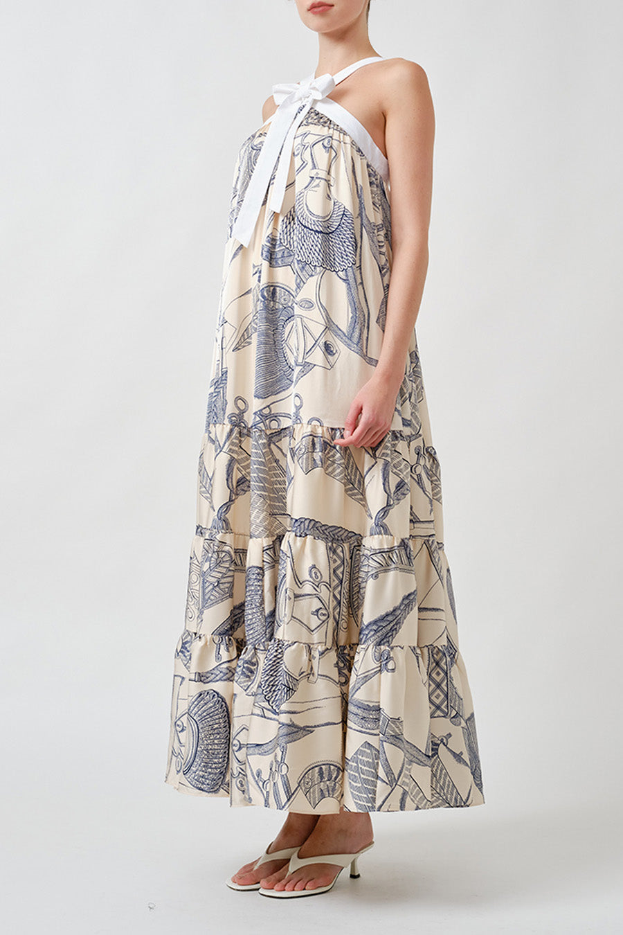 Crafted in a fluid ivory-toned fabric, it features an elegant neck tie that forms a soft bow, creating a refined focal point at the neckline.