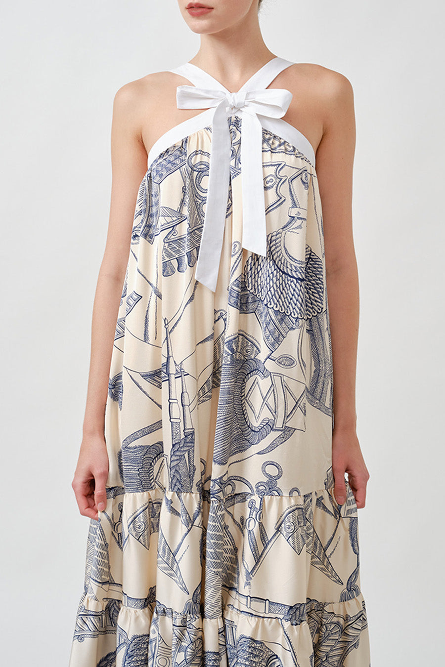 The silhouette falls with gentle volume, enhanced by a tiered hem that adds depth and femininity.