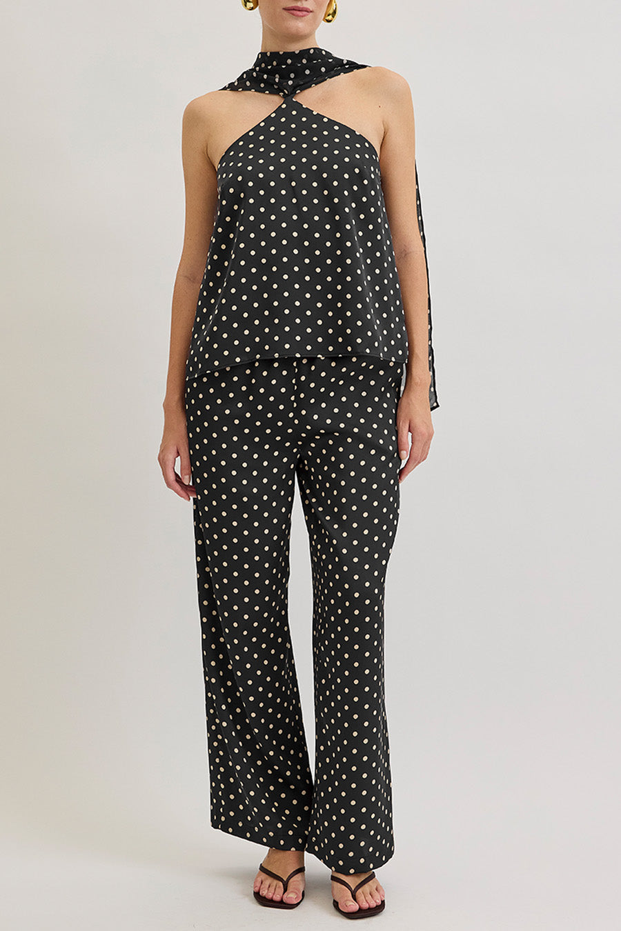 A study in effortless allure, this luxury halter top reimagines timeless polka dots through a modern, architectural silhouette.