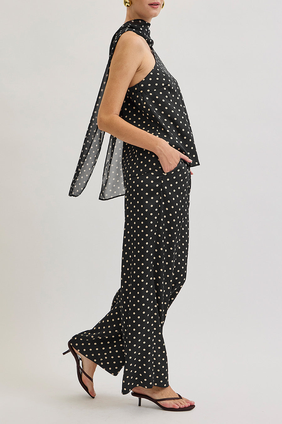 Crafted with a fluid drape, the design features an elegant cross-halter neckline that frames the shoulders and décolletage with subtle drama, while the softly flowing body creates graceful movement.