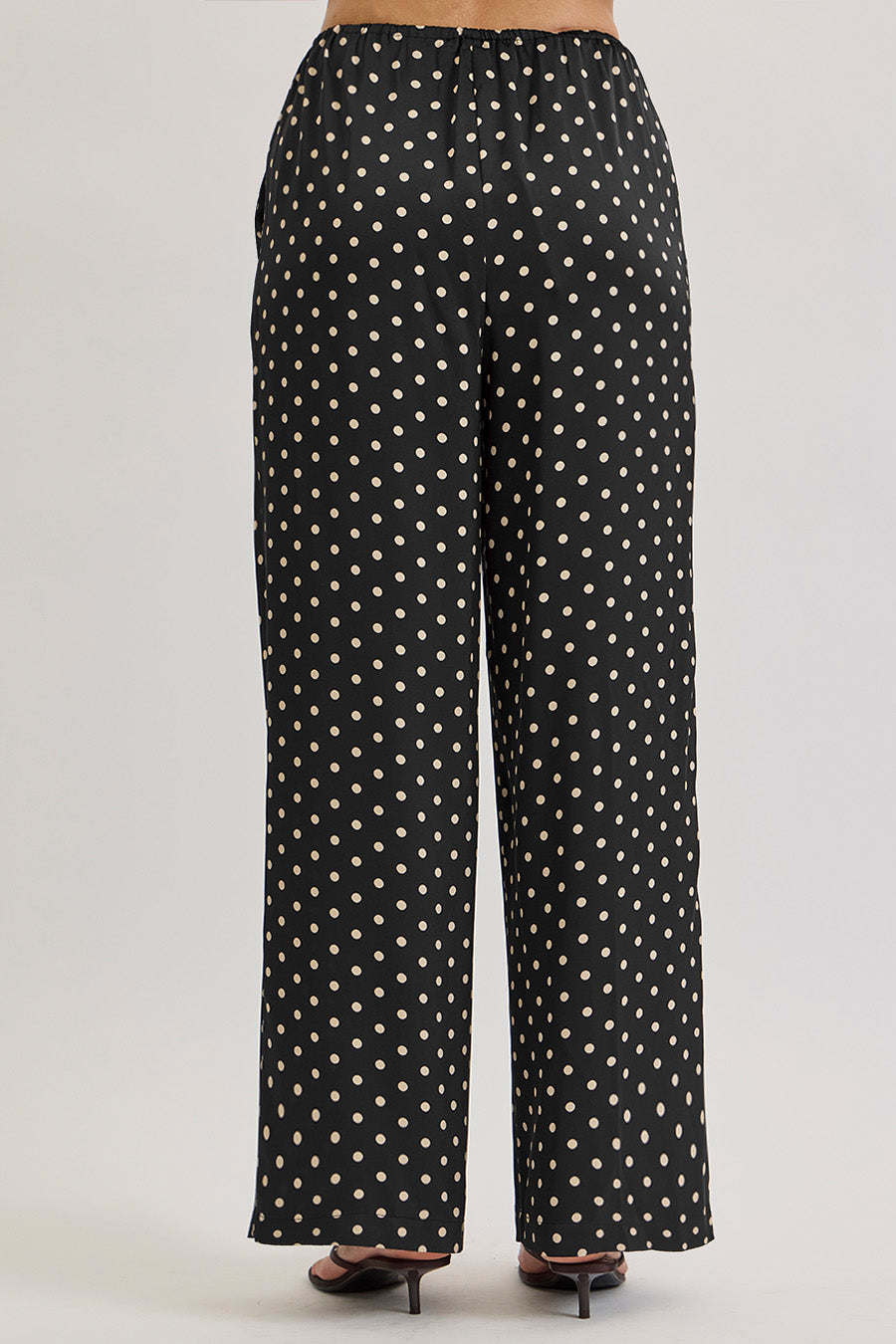 The classic black base is adorned with delicate ivory polka dots, offering a timeless motif reimagined for modern dressing.
