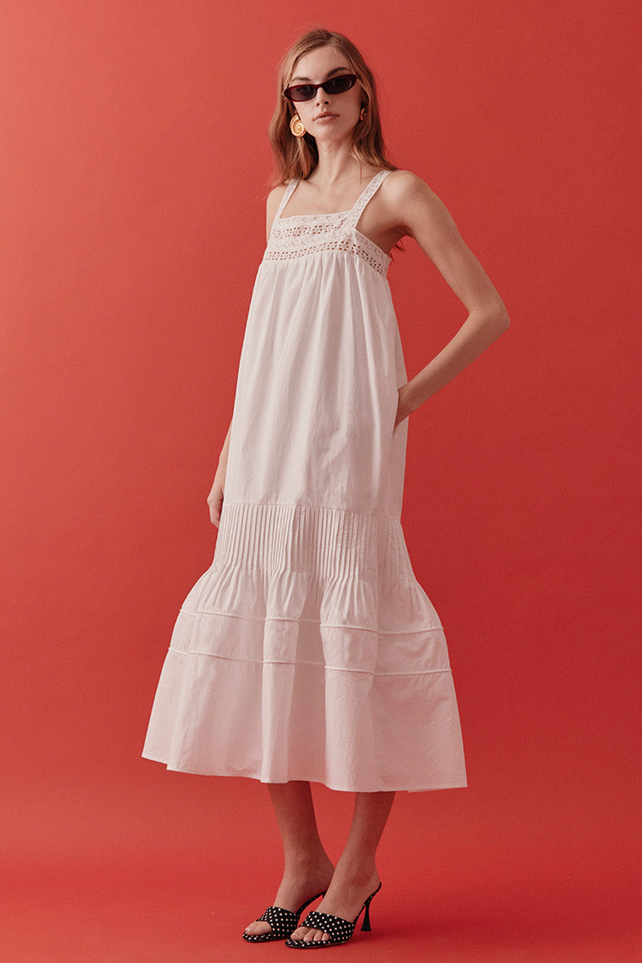 Designed with delicate lace detailing at the neckline and a softly flowing, tiered skirt, the silhouette evokes timeless romance with a modern sensibility.