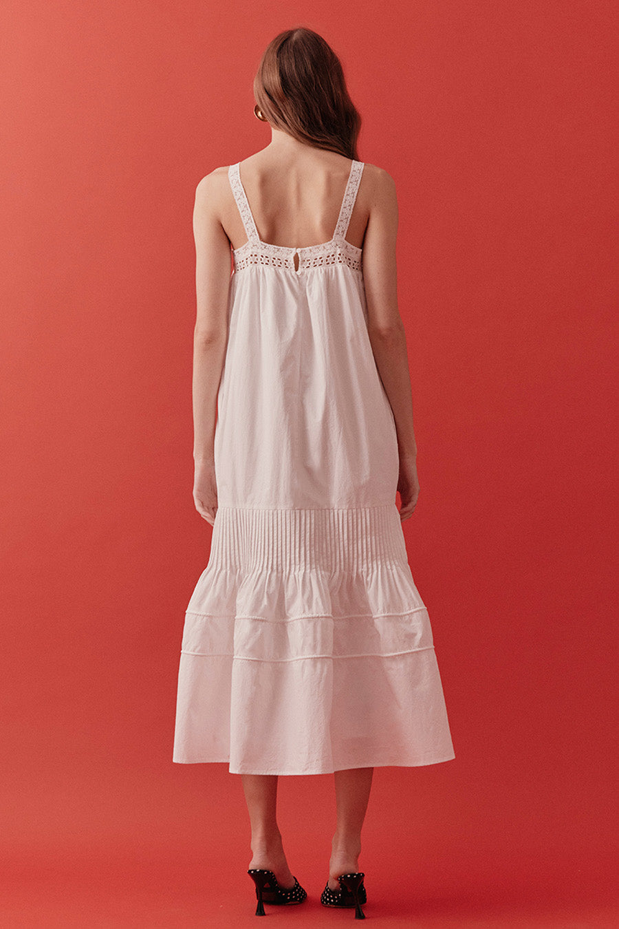 The relaxed bodice offers ease and movement, while subtle pleating and layered tiers add depth, texture, and graceful volume