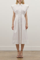 Thoughtfully placed vertical seams and sculpted pleats define the waist and flow into a softly flared midi skirt, enhancing movement and flattering the figure