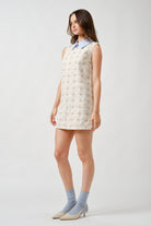 The ivory fabric is adorned with an embroidered grid motif, creating subtle texture and depth that elevates the clean silhouette.