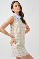 Finished with a crisp contrast collar in pale blue, the design introduces a fresh, contemporary accent that frames the neckline with quiet sophistication.