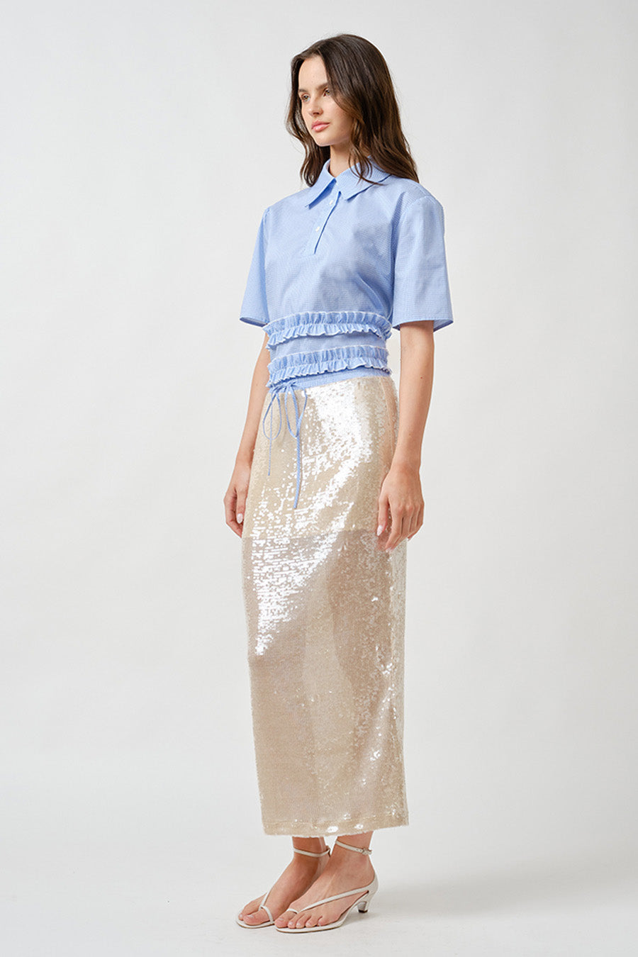 The lightweight blue gingham fabric brings an airy, effortless feel, while the cropped length and layered detailing add dimension and movement.