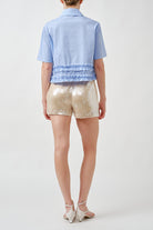 Designed with a sharp pointed collar and clean button placket, it offers a polished upper profile that contrasts beautifully with the softly tiered ruffle hem.