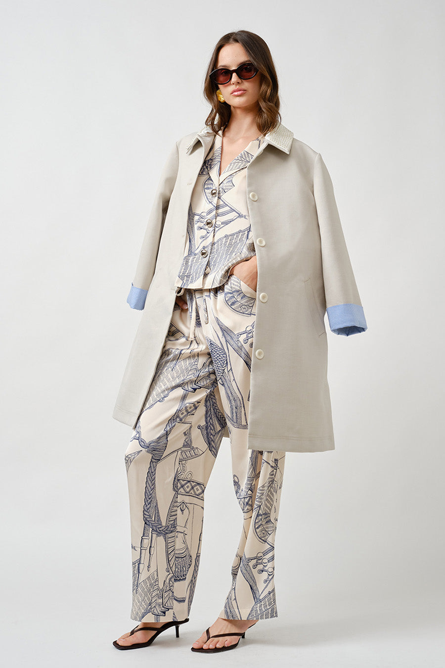 The classic collar and minimalist button closure create a timeless foundation, while subtle contrast lining at the cuffs introduces a discreet, contemporary detail.