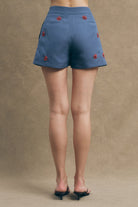 he Roma shorts elevate the summer staple through precise tailoring and hand-applied floral appliqués